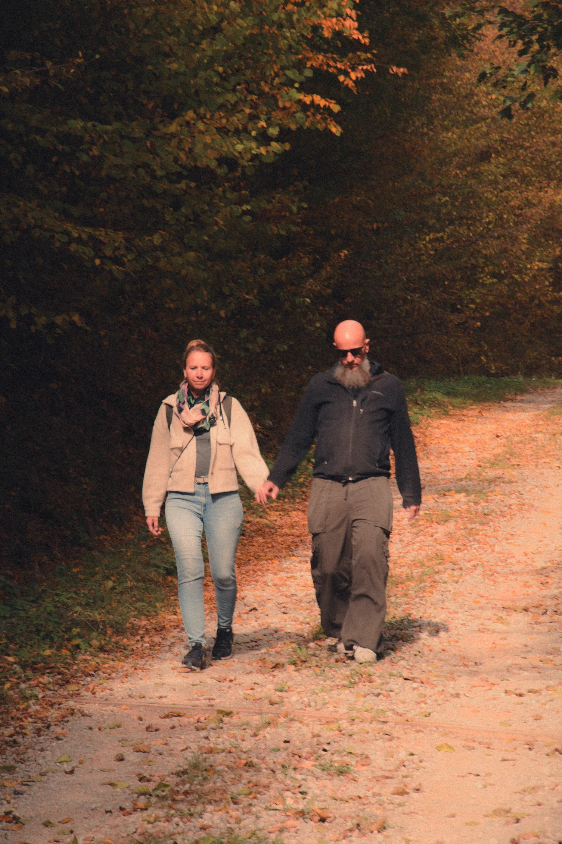 Two people walking towards the camera on a forest path
