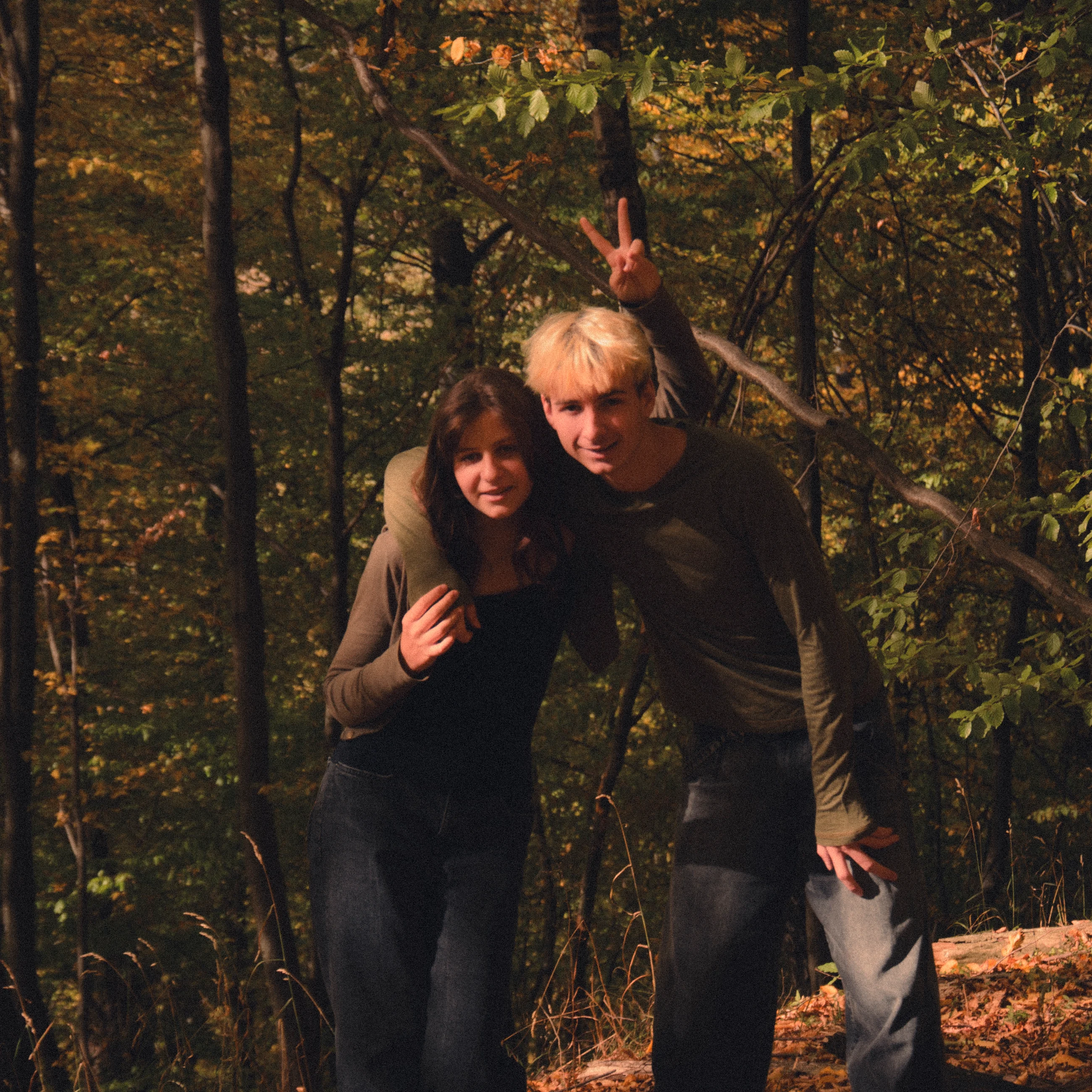 Two people standing together in the woods