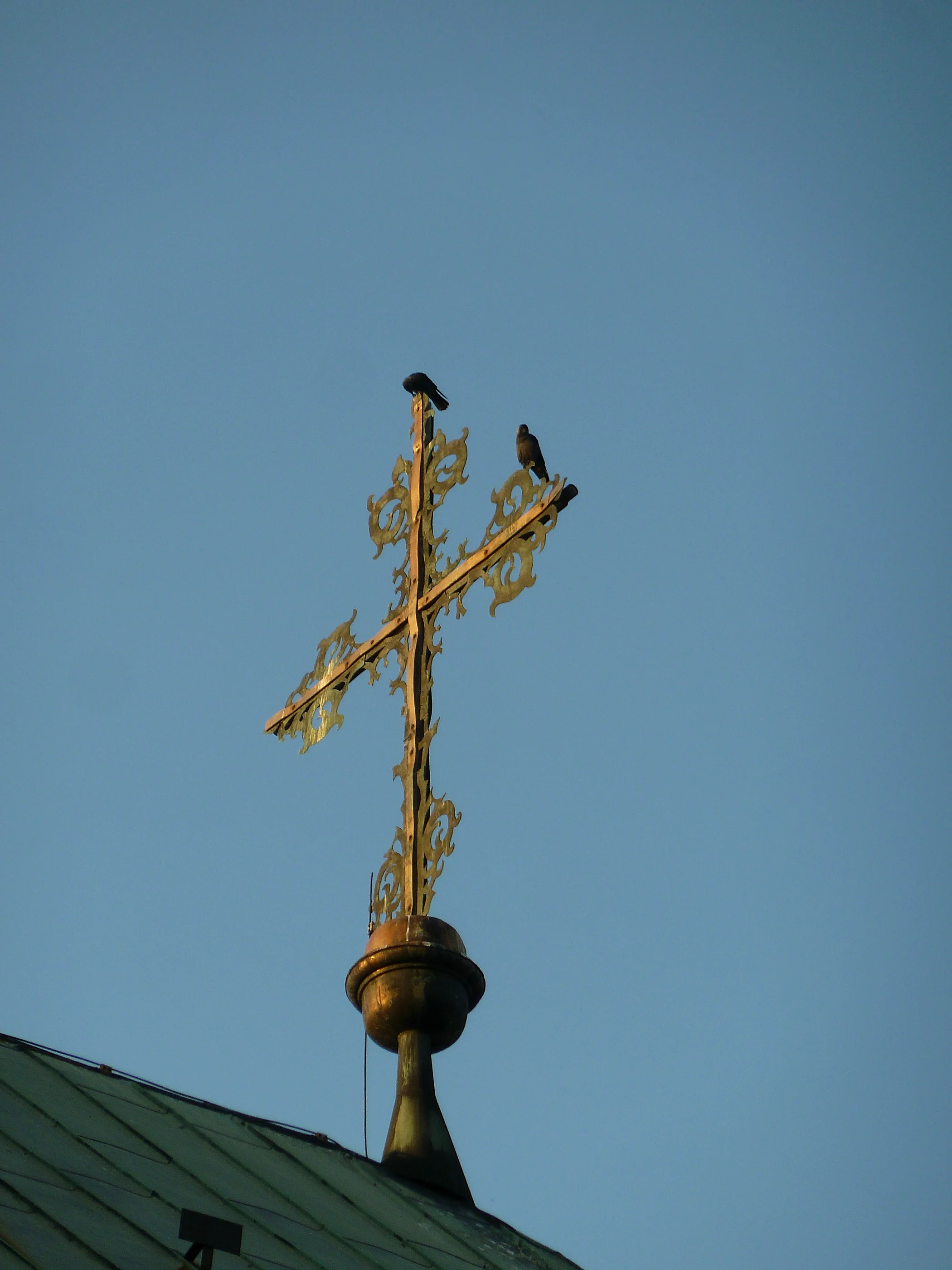 A gilded rooftop cross against a clear blue sky