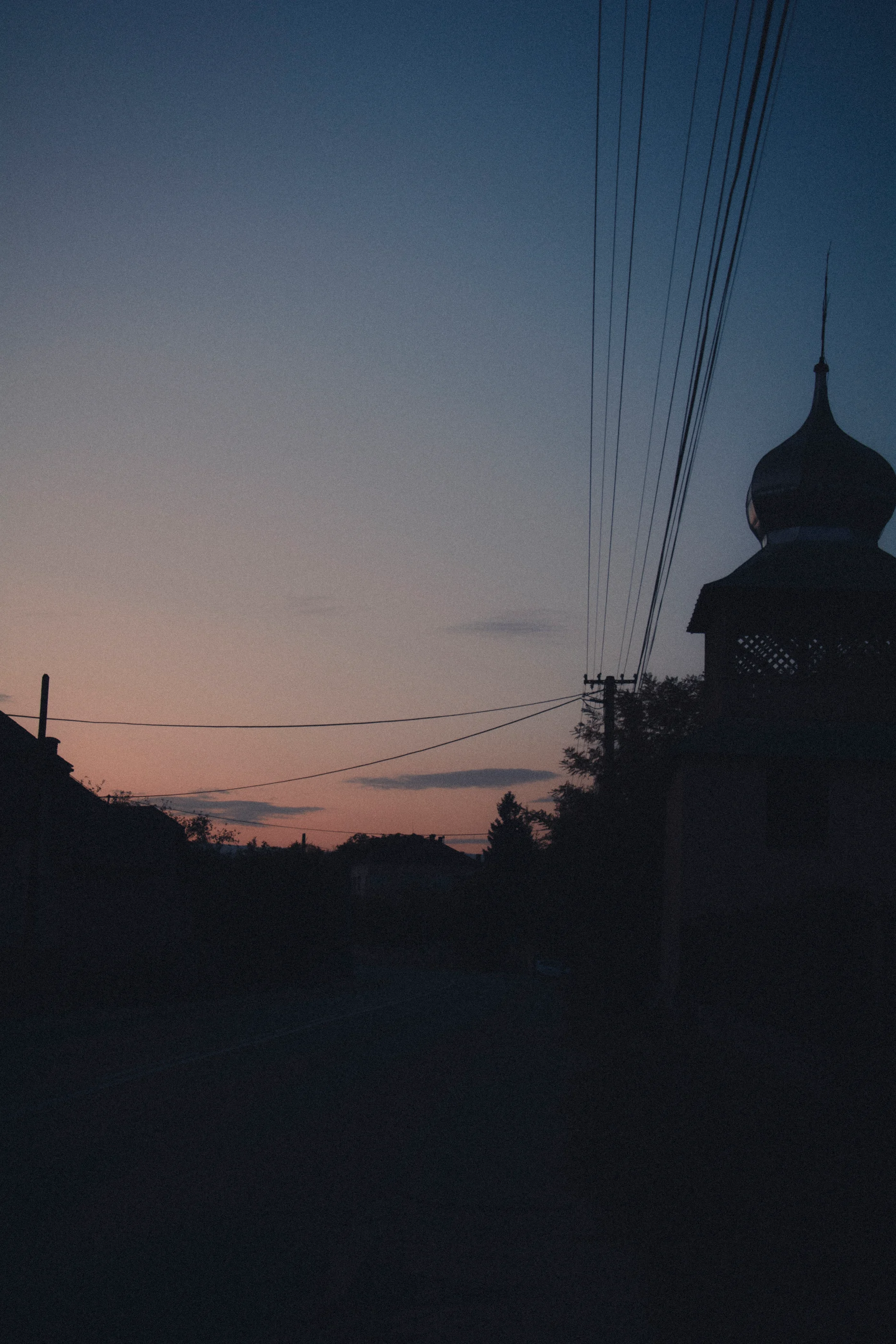 A tower and power lines silhouetted against the twilight sky